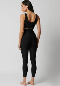 Czarny, bezszwowy stanik sportowy i legginsy z wysokim stanem, charakteryzujące się dopasowanym krojem i gładką fakturą. Minimalistyczny styl bez widocznych elementów metalowych.