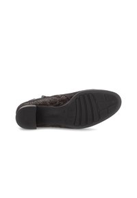 Semelle de chaussure noire texturée avec une surface à motifs, présentant un léger talon et un design rainuré. Marquée "Gabor" sur le côté.