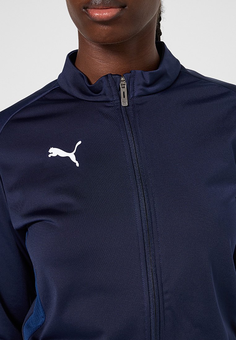 Chaqueta de punto navy con cierre de cremallera y cuello alto, con tejido texturizado, logo blanco en el lado izquierdo del pecho y acentos en azul de contraste a los lados.