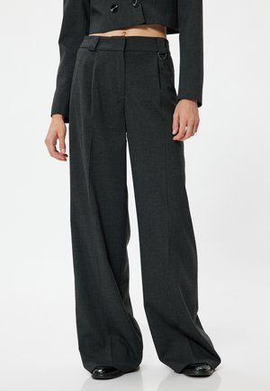 Pantalons larges gris avec un tissu texturé, présentant une taille haute, des poches latérales et des passants de ceinture. Fini lisse et plis subtils.