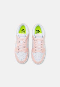 Sneakers with a white leather base and light pink accents, featuring a perforated toe, white laces, and bright green insoles with a black logo.
