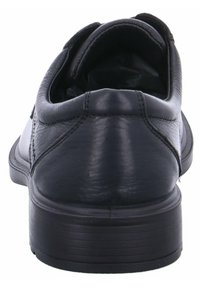 Chaussure de ville en cuir noir vue de l'arrière, avec des coutures visibles, un col rembourré et un talon empilé solide.