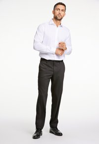 Witte lange mouwen overhemd met knopen, gecombineerd met zwarte formele broek en zwarte schoenen. Schone lijnen en een slim-fit ontwerp. Geen patronen of versieringen.