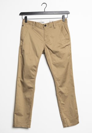 Beżowe, dopasowane, casualowe spodnie z guzikiem i zamkiem błyskawicznym, szlufkami na pasek, kieszeniami bocznymi, zawieszone na czarnym wieszaku na białym tle.