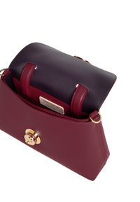 Borsa strutturata in pelle bordeaux profonda, con un cappuccio superiore di un viola scuro in contrasto e hardware dorato. Include un piccolo scomparto interno.