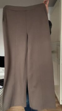 Vida byxor i taupefärgat tyg, med en slät textur, rena linjer och en rak silhuett med sidospjälor vid fållen.