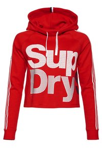 Sudadera corta roja con el texto blanco "Sup Dry" y un patrón de puntos. Presenta una capucha, cordones y acentos de rayas blancas en las mangas.