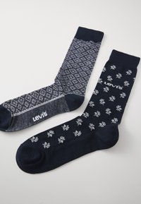 To sæt Levi's sokker: et med et blåt geometrisk mønster, det andet i marineblå med hvide blomster motiver. Begge har ribbede manchetter.