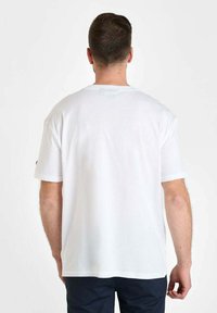 Camiseta blanca de manga corta, tejido de algodón, corte relajado, cuello redondo, vista trasera sencilla, diseño minimalista, sin logotipos ni patrones visibles.