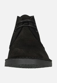 Bottines en suède noir avec un bout rond, deux œillets pour les lacets et une semelle en caoutchouc noir texturé. Design minimaliste avec des lignes épurées.
