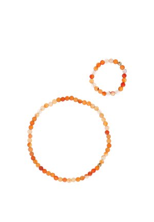 Dwie bransoletki z koralików wykonane z okrągłych pomarańczowych i kremowych koralików, jedna większa, druga mniejsza, na białym tle.
