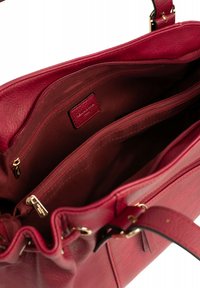 Rode leren handtas met een gestructureerde buitenkant, voorzien van gouden hardware, meerdere binnencompartimenten en een ritsvak.