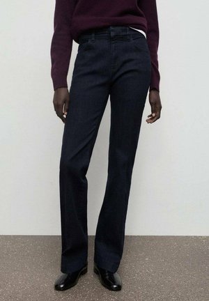 Vaqueros de mezclilla oscura con corte recto, que cuentan con una cinturilla simple, cinco bolsillos y una textura suave. Combinados con un suéter burdeos.