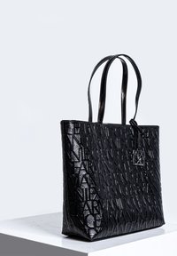 Borsa a tote nera in leather con un motivo a logo in rilievo, design elegante, doppi manici e forma rettangolare. Accompagnata da un piccolo tag.