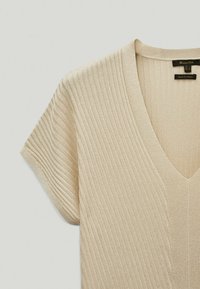 Beiger Rippstrickpullover mit V-Ausschnitt und kurzen Ärmeln. Der Stoff hat eine glatte Textur und betont sein leichtes und atmungsaktives Design.