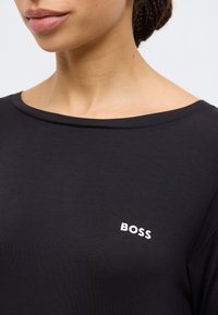 Black T-shirt with a round neckline and a smooth texture, featuring a small white "BOSS" logo on the chest.