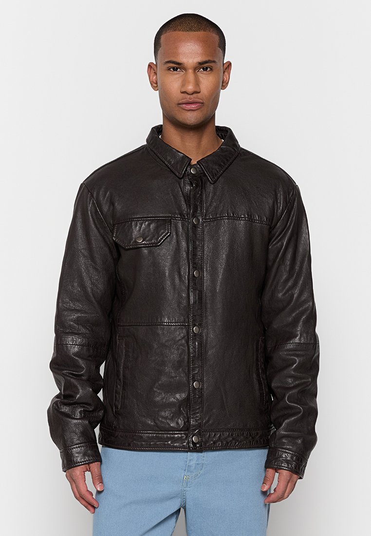 Schwarze Lederjacke mit kragenförmigem Halsauschnitt, vorderem Druckknopfverschluss und einer Brusttasche. Strukturierte Oberfläche mit langen Ärmeln.