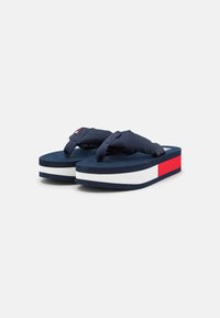 Navy blue flip-flops with thick platform sole featuring white and red stripes. Soft strap design with textured surface for grip.