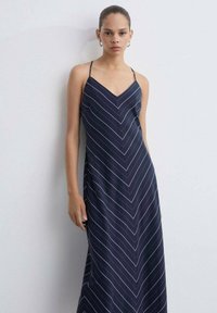 Svetlo moder maxi obleka s tankimi naramnicami, ki prikazuje chevron vzorec v beli barvi. Gladek material z rahlim sijajem in V-izrezom.