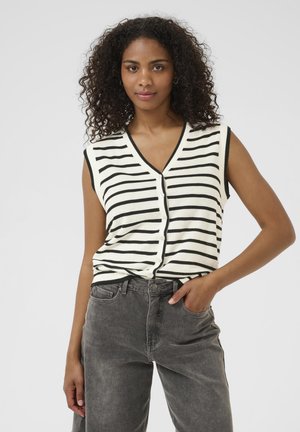 Knitted sleeveless top in cream with black stripes, featuring a V-neckline and button details, paired with gray denim pants.