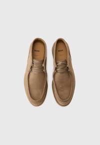 Chaussures en daim beige avec un bout arrondi, un design à lacets et un accent cousu autour du bord. La marque intérieure indique "BOSS".