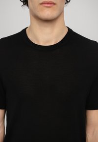 Black, short-sleeve, crew-neck t-shirt made of lightweight fabric with a smooth texture and subtle transparency. Minimal design, no patterns.