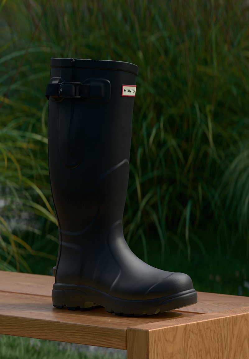 Botas de goma negras tipo Wellington con acabado texturizado, hebilla ajustable y etiqueta de marca. Suela resistente con surcos para mayor tracción.