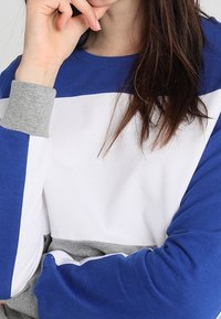 Blå, vit och grå färgblockerad sweatshirt med rund halsringning och ribbade ärmslut. Mjuk textur och avslappnad passform.