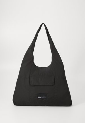 Svart tyg axelväska med triangulär form, bred rem, en liten framficka och en logotyppatch. Slät textur och minimalistisk design.