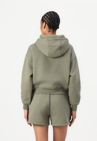 Olivgrüner, verkürzter Hoodie mit Kordelzugkapuze, lockerer Passform und gerippten Bündchen, kombiniert mit passenden Shorts, aus einem weichen Baumwollmischmaterial.