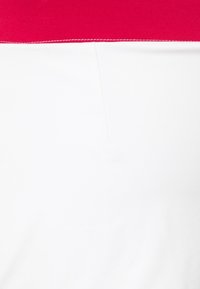 Camiseta sin mangas bicolor en rojo y blanco. La parte superior es roja, mientras que la parte inferior es blanca con una textura suave. Presenta una costura limpia a lo largo del borde.