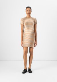 Brun og hvit stripete kortermet kjole med en figurnær design, laget av stretchy materiale, som når midt på låret. Brukt med svarte loafers.