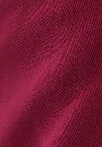 Burgundská pletená látka s texturovaným povrchem, vykazující jemné žebrování a měkký, pohodlný vzhled.