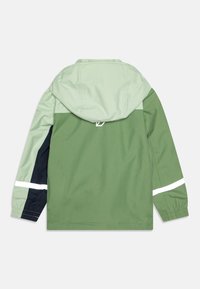 Veste imperméable de couleur vert clair avec un design de blocs de couleur vert foncé et marine. Comprend une capuche et des bandes réfléchissantes blanches.