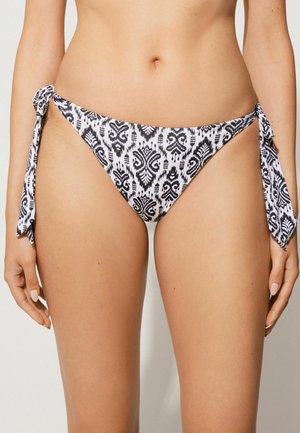 Bikini-Höschen mit Bindebändern an den Seiten, verziert mit einem schwarz-weißen Muster, aus glattem Stoff mit weicher Textur. Verstellbare Bänder auf jeder Seite.