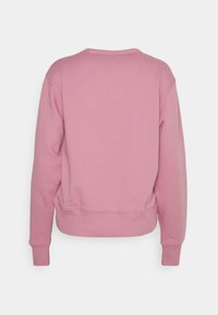 Sweat-shirt rose avec encolure ronde, manches longues et poignets côtelés. Texture lisse, coupe légèrement courte et design épuré et simple.