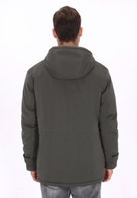 Chaqueta verde oscuro con capucha, textura lisa, mangas largas y ajuste ligeramente holgado. Presenta una costura en la cintura y detalles en los puños.