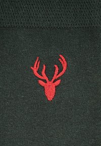 Ciemnozielone skarpetki z teksturowanym wzorem dzianiny i czerwonym haftowanym logo głowy jelenia umieszczonym na środku przodu.