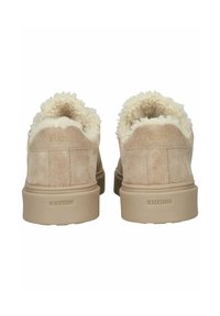 Dvojice béžových semišových slip-on bot s huňatým krémovým podšitím viditelným kolem límce, z pohledu zezadu, s brandingem "Blackstone" na patách.