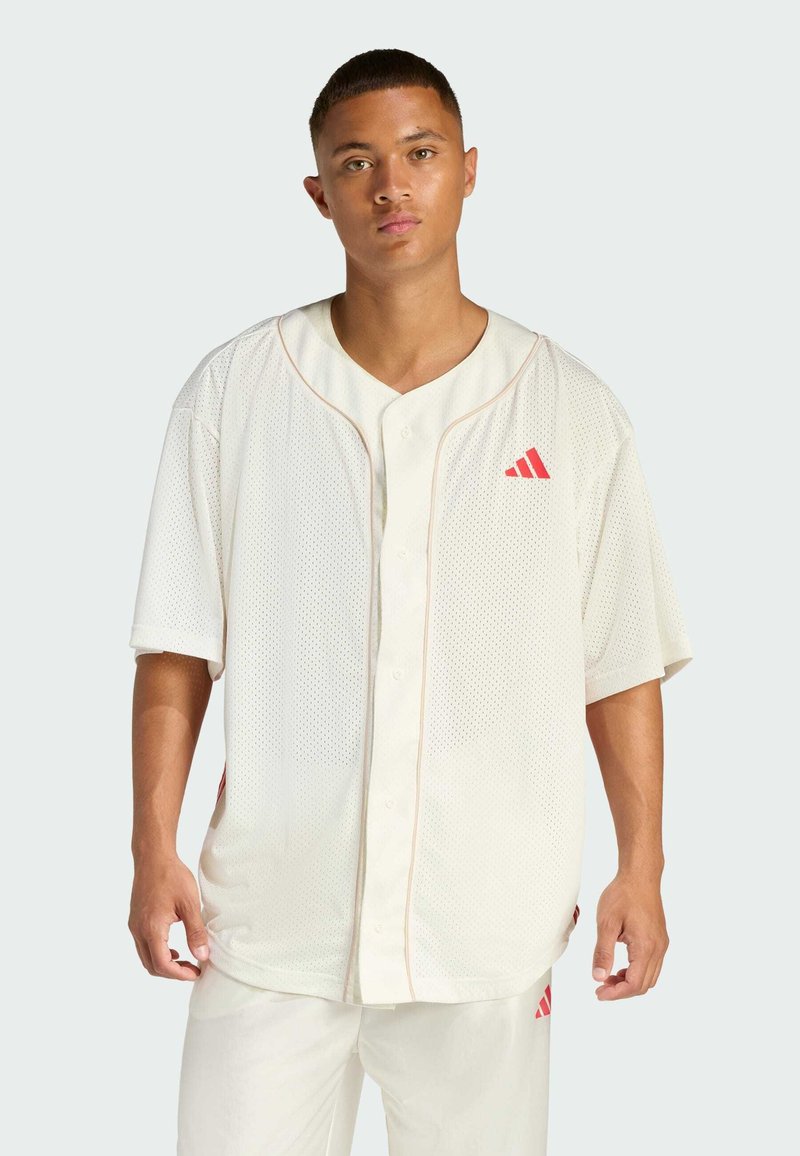 Maglia da baseball bianca in rete con maniche corte, scollo a V, dettagli rossi e logo. Presenta una chiusura a bottone e spacchi laterali per comfort e vestibilità.