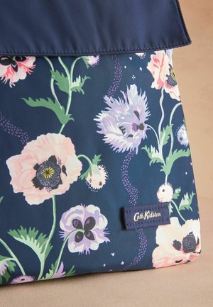Laivyno mėlynumo gėlėta medžiaga su rožinėmis ir violetinėmis gėlėmis bei žaliomis lapelėmis, papuošta baltai siuvinėta "Cath Kidston" etikete.
