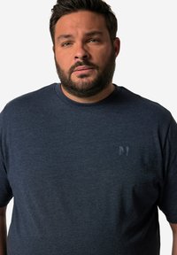 Granatowa koszulka z okrągłym dekoltem, wykonana z miękkiego materiału, z małym, subtelnym logo z przodu. Krótkie rękawy, luźny krój.