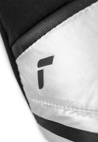 Tessuto nero e argento con una trama liscia, caratterizzato da un logo nero prominente su uno sfondo argentato e un dettaglio di cucitura.