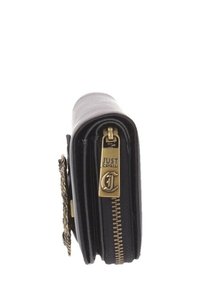 Portafoglio in pelle nera con zip e hardware in tonalità oro, dotato di etichetta con logo. La vista laterale mostra la forma compatta e i dettagli cuciti.