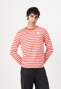 Langärmliges T-Shirt mit rot-weißen Streifen, rundem Ausschnitt und kleinem weißen Logo auf der Brust, aus weichem Baumwollstoff gefertigt.