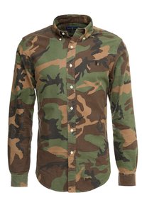 Camisa de botones con patrón de camuflaje que presenta tonos verdes, marrones y negros. Hecha de algodón, tiene cuello con solapa y mangas largas.