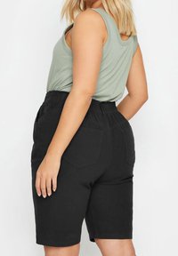 Svarta shorts med elastisk midja och fickor, tillverkade i ett mjukt tyg. Modellen har på sig en ljusgrön ärmlös topp.