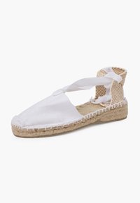 Espadrillas in tela bianca con punta rotonda, suola in juta intrecciata e lacci che si avvolgono alla caviglia. Presentano un tacco beige testurizzato e dettagli di cucitura.