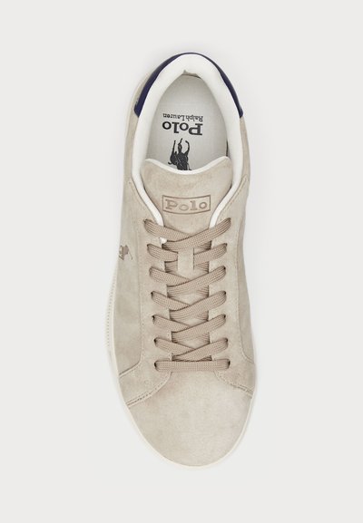 Bež usnjeni čevlji s krožno konico, teksturirano površino, ravnimi vezalkami, oznako logotipa in kontrastnim mornarsko modrim poudarkom na peti. Bela gumijasta podplat.