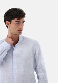 Himmelblaues, langärmeliges Hemd mit Stehkragen, das ein dezentes strukturiertes Muster und eine Knopfleiste aufweist.